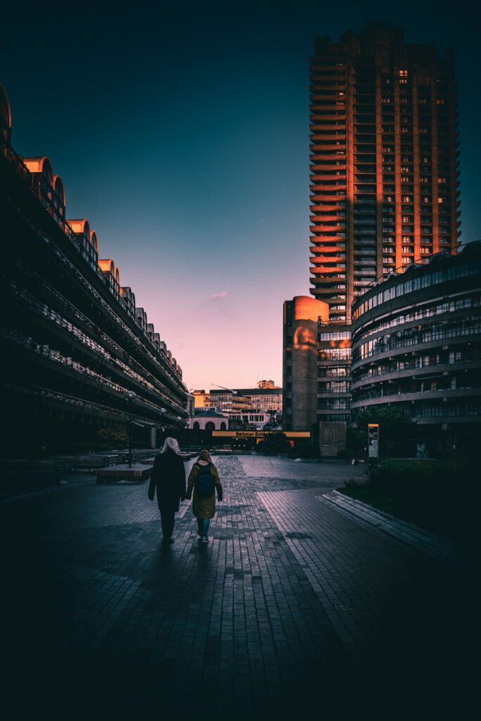 para spacerująca podczas zachodzącego słońca w centrum barbican z widoczną architekturą brutalizmu