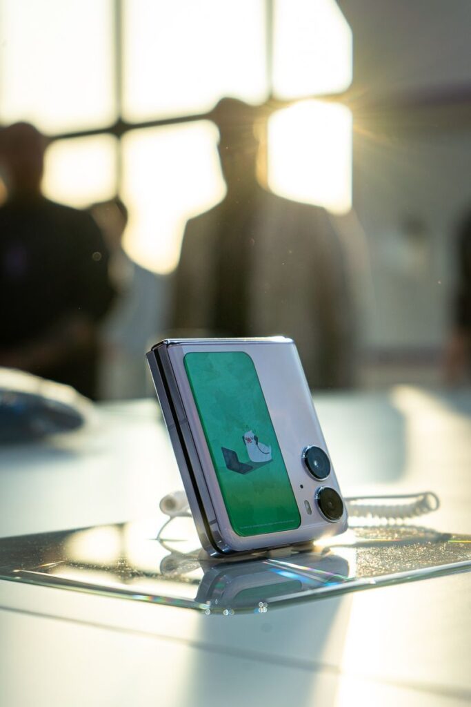 Wystawowy telefon oppo find n2 flip złożony. Sylwetka człowieka w tle
