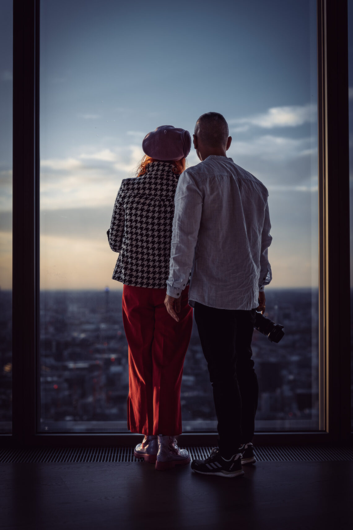 para fotografów spoglądających na Londyn z wieżowca