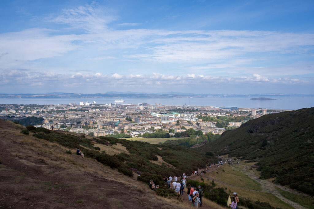 Tłum ludzi wchodzących na górę na punk widokowy Arthur's seat koło Edynburga.